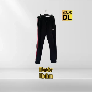 Moncler Tricolor Mjukisbyxor - (Moncler Tricolor Track Pants) Svarta mjukisbyxor från Moncler. Avsmalnande ben med ribbade benslut, elastisk midja och utsmyckad med den ikoniska tricolor stilen. 100% bomull. Två sidofickor. Perfekt för en avslappnad look med en touch stil. Inköpspriset ligger runt 5-6 tusen. Använda ett par gånger i hemmet, praktiskt taget i nyskick. 