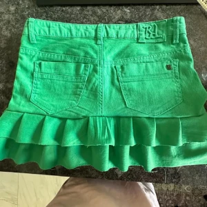Grön volangkjol  - Snygg grön kortkjol från Bondelid i jeansmaterial med volangkant nertill. Älskar den här - säljer för har en liknande! Perfekt nu till sommaren när man är brun