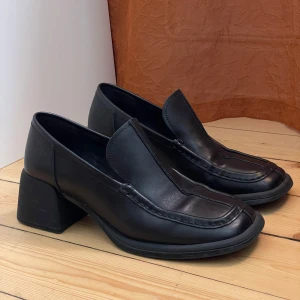 Loafers med fyrkantig tå och klack från Vagabond - Chunky svarta loafers från Vagabond i skinn med fyrkantig tå och bred blockklack. Minimalistisk design med markerade sömmar. Strl 40 men är stora så passar nog strl 41 bättre. Lite skav på klacken men är relativt oanvända