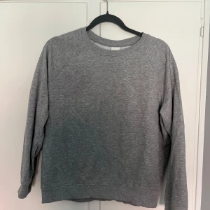 Grå sweatshirt från H&M  - Enkel och stilren grå sweatshirt från H&M Basics i storlek S. Tröjan har rund halsringning, långa ärmar och är tillverkad i mjuk bomullsblandning. Perfekt för en chill och avslappnad look.
