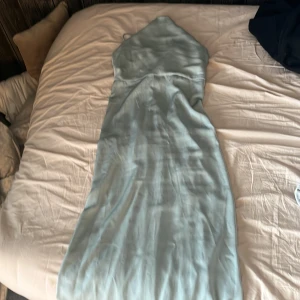 Ljusgrön långklänning från Bubbleroom - Supersnygg ljusgrön långklänning från Bubbleroom med smala axelband och v-ringning. Klänningen har en elegant, figurnära passform och är gjord i ett glansigt satinliknande material . Perfekt för bal eller student! Användt en gång på 9ans middag, köpt för 550kr