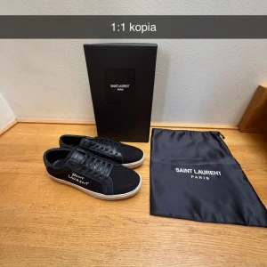 Saint Laurent skor - Snygga svarta sneakers från Saint Laurent med vit logga på sidan och vit sula. Skorna har klassisk snörning, rund tå och detaljer i skinn och textil. Skorna är helt ny, däremot är boxen lite söndring efter frakten 