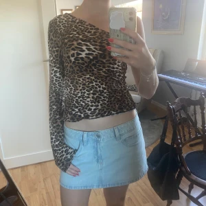 Leopardmönstrad oneshoulder topp - Säljer en snygg leopardmönstrad topp från NA-KD i oneshoulder-modell. Toppen är figurnära med lång ärm på ena sidan och ärmlös på andra. Materialet är mjukt och stretchigt, perfekt för att sticka ut. Passar dig som gillar trendiga och djurmönstrade plagg.