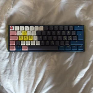 Ducky one 3 mini customized - Bilderna visar ett Ducky One 3 Mini-tangentbord i blått och gult med färgglada keycaps. Tangentbordet är kompakt och populärt bland gamers och unga vuxna som gillar att anpassa sin setup. Perfekt för dig som vill ha en snygg och smidig lösning till datorn. Ända problemet är att skruvarna är borta men funkar fortfarande perfekt, visa switches är utbyta till panda switches. 