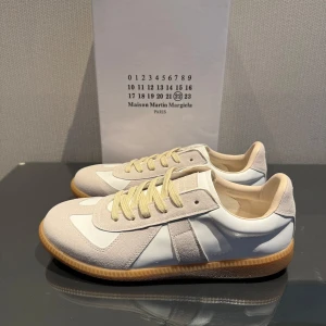 Maison Margiela Gats - Maison Margiela gat sneakers i vitt och beige. Skorna är helt nya och är i storlek 43. Säljer pågrund av att de var lite för stora för mig. Perfekta skor till sommaren som kommer ge dig en clean look☀️ Vid funderingar är det bara att höra av sig‼️