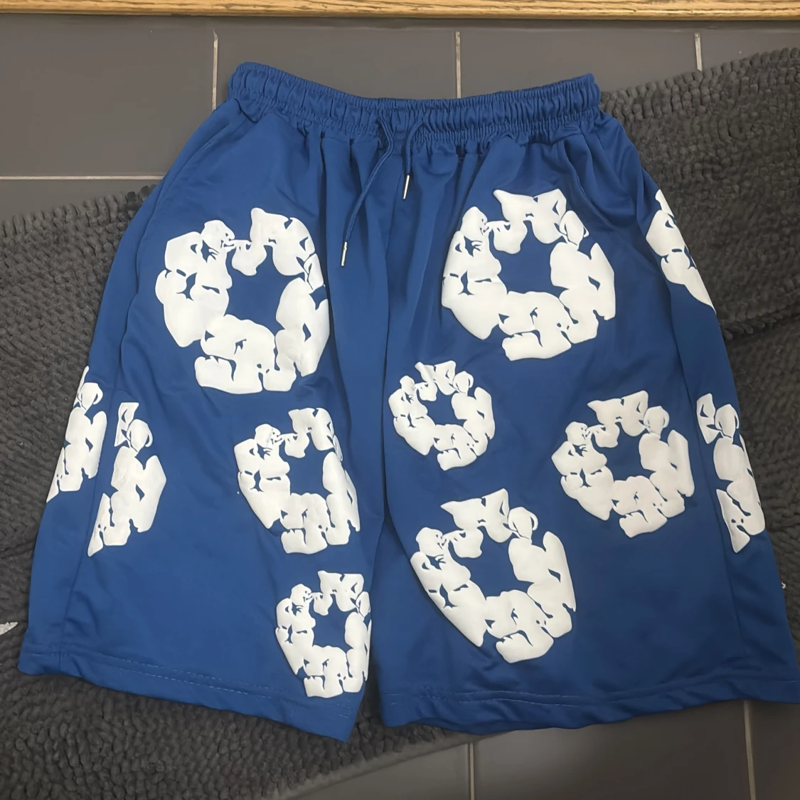 Blå shorts med vit blommig print från Denim Tears