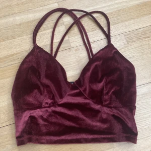 Vinröd sammetslinnetopp med korsade axelband från Bik Bok - Säljer en vinröd croppad linnetopp i sammet från Bik Bok. Toppen har tunna korsade axelband och en mjuk, glansig yta. Perfekt för att lyfta en outfit med lite extra lyxig känsla.