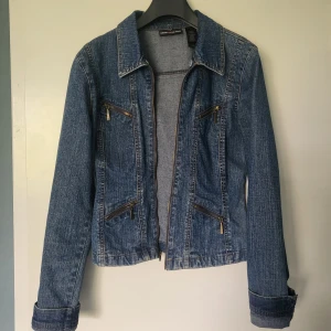 Jeansjacka från DKNY Jeans - Säljer en klassisk blå jeansjacka från DKNY Jeans med dragkedja och fyra snedställda fickor med dragkedjor. Jackan har lång ärm, markerad krage och figurnära passform.  Passar både xs och s beroende på hur man vill ha det. Perfekt till vår och sommar!☀️