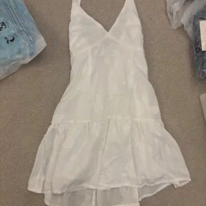 Vit kortklänning med volang från Peppermayo - Superfin vit kortklänning från Peppermayo med v-ringning och volang nertill och halterneck. Superfin men var tyvärr för liten för mig. Storlek 34, AU 6, US 2. Endast provad, alla lappar kvar.