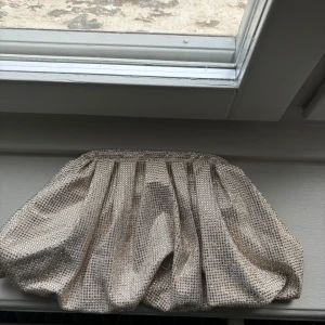 Glittrig kuvertväska från STOCKH LM Studio - Säljer en glittrig kuvertväska i guld från STOCKH LM Studio. Väskan har ett skimrande yttertyg med små glitter stenar och ett ljust innerfoder. I väskan är det mycket rymligt med plats för mycket, har även ett mindre innerfack. Man stänger den med magnet (mycket stark så ingen risk att den öppnar sig själv). Den är använd två gånger och är i jätte bra skick.