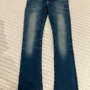Blå Replay jeans slim bootcut ”24” - blå jeans från Replay i modell Rearmy slim bootcut. Jeansen har klassisk femficksdesign, lätt slitna detaljer och normal passform upptill med utsvängda ben. Perfekta för dig som gillar en tidlös jeansstil. Waist 24 length 32.