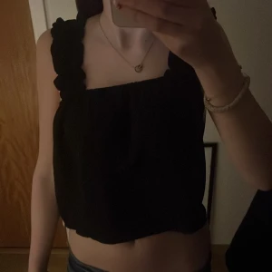 Svart croppad linnetopp med volangband - Säljer en svart croppad linnetopp med breda, volangprydda axelband. Toppen har en fyrkantig urringning och är tillverkad i ett mjukt, lätt material. Perfekt att styla med jeans eller kjol😻 pris går att diskutera🥰