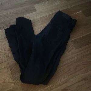 Svarta jeansbyxor från Gina Tricot - Svarta jeansbyxor från Gina Tricot, tillverkade i bomull från deras good collection. Klassisk femficksmodell med normal passform och hög midja. Perfekta till vardags och enkla att matcha med olika toppar.