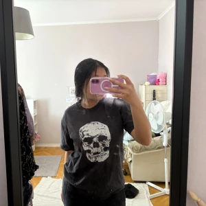 Svart t-shirt med dödskalletryck - Cool svart t-shirt från Fruit of the loom med stort vitt dödskalletryck på framsidan. Klassisk passform med rund hals och korta ärmar. Perfekt för dig som gillar edgy och streetwear-stil.