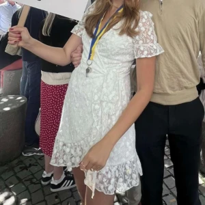 Vit spetsklänning med volang och omlott, - Superfin vit kortklänning med spetsdetaljer och volangkant. Klänningen har omlottmodell, v-ringning och korta spetsärmar. Perfekt för student eller sommarens festligheter! Enastående Använd 1 gång