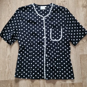 Svart blus med vita prickar  - Söt blus med vita knappar och brodyr.