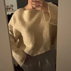 Beige stickad tröja med oversized passform - Mysig beige stickad tröja med oversized passform och långa ärmar. Tröjan har en enkel design utan synliga detaljer och är perfekt för en avslappnad stil.