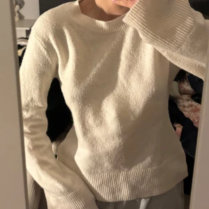 Vit stickad tröja - Mysig vit stickad tröja med rund halsringning och långa ärmar. Tröjan har ribbade muddar vid ärmslut och nederkant, perfekt för kyligare dagar. Enkel och stilren design som passar till mycket.