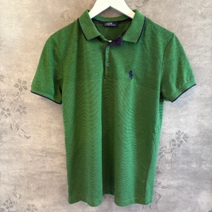 Ralph Lauren piké - Vill du sticka ut på ett stilrent sätt? Den här gröna Ralph Lauren-pikén har en riktigt snygg, annorlunda nyans och diskreta kontrastdetaljer  Ralph Lauren, Polo Ralph Lauren, Pikétröja herr, Preppy stil, Klassisk piké, Designer piké, Streetwear, Herrmode, Loggopiké, Sommarstil, Snygg piké, Trendigt plagg.  #ralphlauren #pikétröja #green #unikstil #preppylook #herrkläder  Storlek: L Barn, men passar som s / xs Skick: Ny utan prislapp Pris: 230 (men kan diskuteras vid snabb affär)