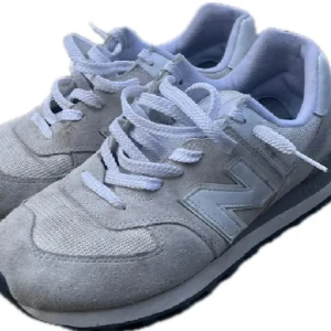Vita New Balance sneakers - Säljer ett par klassiska vita New Balance sneakers med grå detaljer och vit sula. De är i storlek 44 men passar 43/42 bättre, pris 439kr!