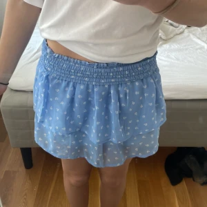 Blå volangkjol med småblommigt mönster från Kappahl - Supersöt blå kjol från Kappahl med vita små blommor och dubbla volanger. Perfekt för sommaren💗Diskuterar gärna pris💕