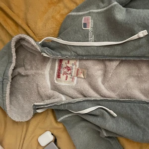 Grå hoodie från True Religion - Mysig grå hoodie från True Religion med vit dragkedja och fodrad insida. Kom med bud! Inga defekter! Priset är förhandlingsbart!