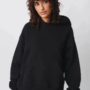Svart hoodie från Gina tricot  - Säljer en klassisk svart hoodie med huva och magficka. Tröjan har en avslappnad passform och långa ärmar, perfekt för en chill och enkel stil.