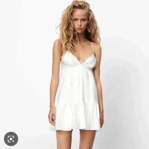 Vit kort klänning  - Söt vit kortklänning med smala axelband och v-ringning. Klänningen har en luftig passform och volang nedtill, perfekt för varma dagar. Tillverkad i ett lätt material som känns skönt mot huden. Säljer den då den tyvärr va för liten, den är aldrig använd och därav mycket bra skick🥰