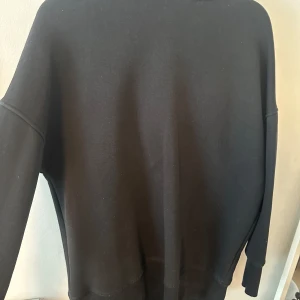 Svart hoodie från Bianca - Säljer en svart hoodie från Bianca ingrossos märke i storlek XXS. Tröjan har en klassisk huva och långa ärmar, perfekt för en avslappnad stil. Den är lite overzise så storleken passar till en XS-S