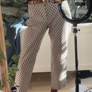 Byxor från Banana Republic - Snygga vita byxor från Banana Republic med svart rutigt mönster. Byxorna har normal passform och raka ben, perfekta för en trendig och stilren look. Stängs med dragkedja och knapp framtill. Superskönt stretchigt material. Har aldrig använts och är i mycket bra skick!