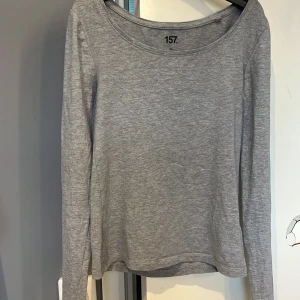 Grå långärmad topp från 157 - En enkel och stilren grå långärmad topp från 157. Tillverkad i mjuk bomullsblandning med rund halsringning. Perfekt basplagg att ha i garderoben.