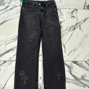 Chrome Hearts Jeans - Säljer ett par svarta jeans från Chrome Hearts med flera broderade korsdetaljer på både fram- och baksidan. Byxorna har raka ben