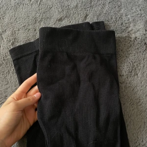 Svarta ribbade leggings från ONLY PLAY - Säljer ett par svarta ribbade leggings från ONLY PLAY. De har bred resår i midjan och är gjorda i ett stretchigt material som sitter tight. Perfekta för träning eller chill. Snygg och enkel design som passar till det mesta.