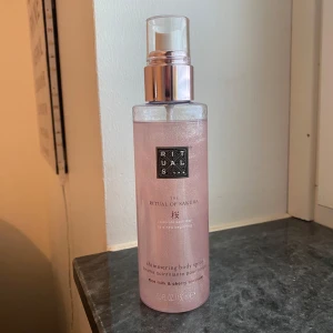 Rituals The Ritual of Sakura Shimmering Body Spray - En lyxig kroppsspray med skimmer från Rituals, The Ritual of Sakura. Doft av ris och körsbärsblom. Kommer i en genomskinlig rosa flaska med pump och silvrig kork. Perfekt för att ge huden en glittrande finish. Endast testat 1 gång annars är den helt ny. 