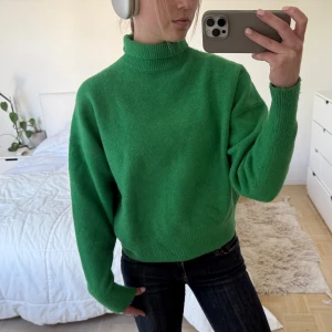 Grön stickad polotröja - Säljer en snygg grön stickad polotröja med hög krage. Tröjan har lång ärm och är lite oversized i modellen. Perfekt att styla med jeans eller kjol för en cool look.