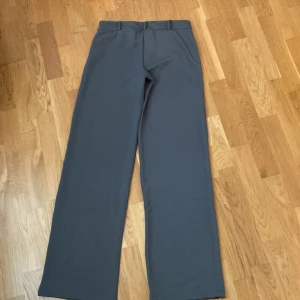 Grå lågmidjade kostymbyxor från Nelly - Snygga grå kostymbyxor från Nelly med raka, vida ben och klassisk passform. Byxorna har hällor för bälte och stängs med knapp och dragkedja. Perfekta för en stilren look. 🙌💗