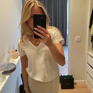 Vit blus med spetsärmar - Säljer en söt vit blus med v-ringning och korta ärmar i spets. Enkel och stilren design som passar till mycket.