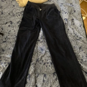 Blåa mjukisbyxor från Juicy Couture - Mysiga blåa mjukisbyxor från Juicy Couture med resår och snörning i midjan samt två fickor bak med silverfärgade knappar. Perfekta för en avslappnad stil och supermjuka i materialet.