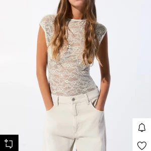 Vit spetsbody med blommönster - Säljer en vit body i transparent spets med blommigt mönster. Bodyn har korta ärmar och rund halsringning. Perfekt att styla med jeans eller kjol för en trendig look. Jag har använt den 1 gång och då hade jag en vit tubtopp under🦢