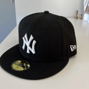 Svart New Era 59FIFTY New York Yankees keps - Klassisk svart New Era 59FIFTY keps med New York Yankees-logga broderad i vitt framtill. Rak skärm och broderad MLB-logga baktill. Kepsen har en stilren look som passar till många outfits.
