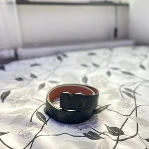 Lv bälte  - Säljer ett svart bälte (HELT NYTT) från Louis Vuitton med klassiskt LV-monogram och svart metallspänne. Bältets insida är ljusbrun och det är tillverkat i skinn. Storlek 105cm. Aldrig använtPerfekt accessoar för att lyfta din outfit. Tveka inte hör av dig vid frågor. 