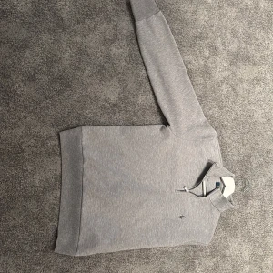 Grå halvzip tröja från Polo Ralph Lauren - Säljer en stilren grå tröja från Polo Ralph Lauren med halv dragkedja och broderad logga på bröstet. Perfekt för lager-på-lager och har en klassisk passform med hög krage.