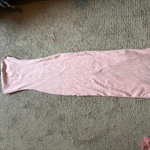 Rosa ribbad långklänning - Säljer en ljusrosa långklänning med ribbad struktur. Klänningen är ärmlös och har en tight passform som framhäver siluetten. Perfekt för dig som gillar en enkel men stilren look.