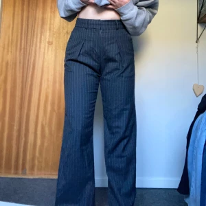 Randiga kostymbyxor från Stockh LM - Stilrena kostymbyxor i en mörkgrå färg med vita tunna ränder. De är högmidjade och köpta från Stockh LM. I storlek 34 men passar mig som har 36/38 vanligtvis:) 