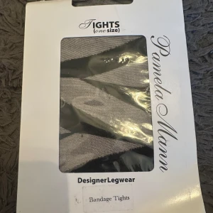 Randiga tights från Pamela Mann - Säljer ett par designer-tights från Pamela Mann i svart och grått med randigt mönster. One size och perfekt för dig som vill ha något unikt till din outfit. Helt nya i onesize.
