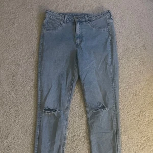 Ljusblå skinny jeans - Säljer ett par ljusblå jeans med slitningar vid knäna. Klassisk femficksmodell med normal passform och hög midja. Perfekta för en avslappnad och trendig look.