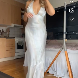 Vit långklänning i satin med djup v-ringning - Säljer en elegant vit långklänning i satin med djup v-ringning och öppen rygg, så fin från zara endast använd en gång! Är en M men jag är oftast en S/Mi klänningar så 