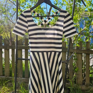 Randig klänning med korsade band i ryggen - Snygg kortärmad klänning med svartvita ränder och korsade band i ryggen. Strl 36 