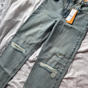 Ljusblå slitna straight jeans från 164 - Säljer ett par ljusblå jeans med raka ben och slitna detaljer på både lår och knän. Modellen är straight 90s jeans, det är från Young avdelning från Gina tricot. Det är aldrig använda och har prislappen på, skriv för mer info💗