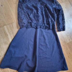 Marinblå spetsklänning Dorothy Perkins - Supersnygg marinblå kortklänning från Dorothy Perkins med blommig spets upptill och trekvartsärm. Kjolen är slät och lätt utsvängd, medan överdelen har transparent spets för en extra cool look. Perfekt för dig som gillar stilrena detaljer och vill sticka ut.